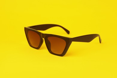 Photo of Stylish pair of sunglasses on yellow background