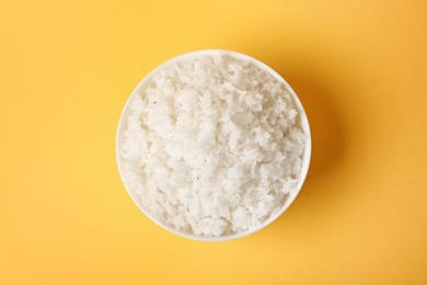 Photo of Bowl of boiled rice on color background, top view