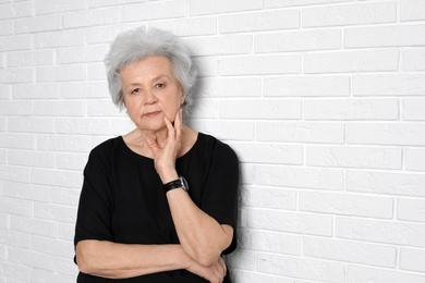 Photo of Portrait of mature woman near brick wall. Space for text