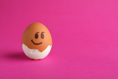 Photo of Egg with drawn face on pink background, space for text. Exhibitionist concept