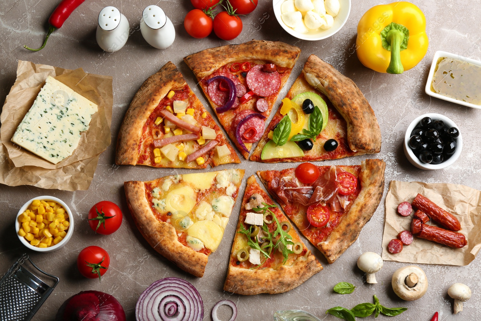 Photo of Flat lay composition with slices of different delicious pizzas on grey marble table