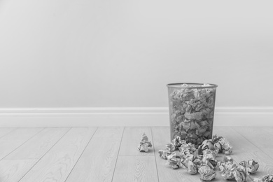 Photo of Metal bin and crumpled paper against light wall, space for text