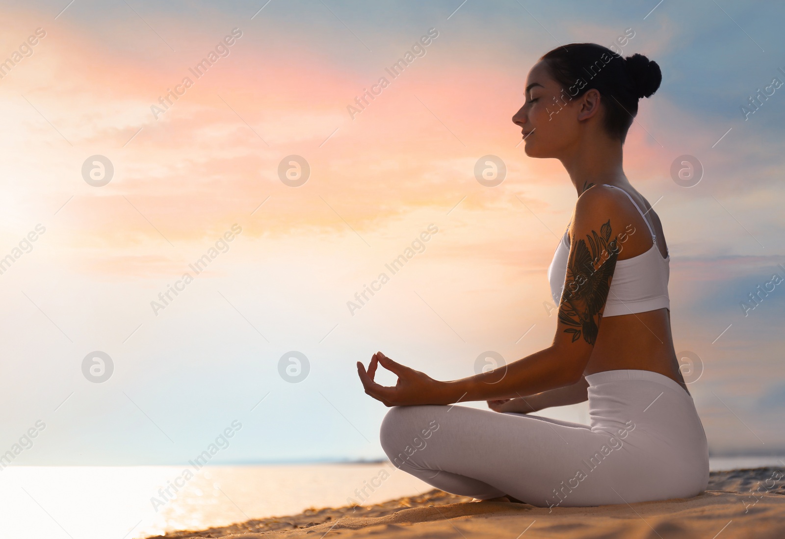 Photo of Young woman practicing zen meditation on beach. Space for text