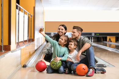 Photo of Happy family taking selfie in bowling club