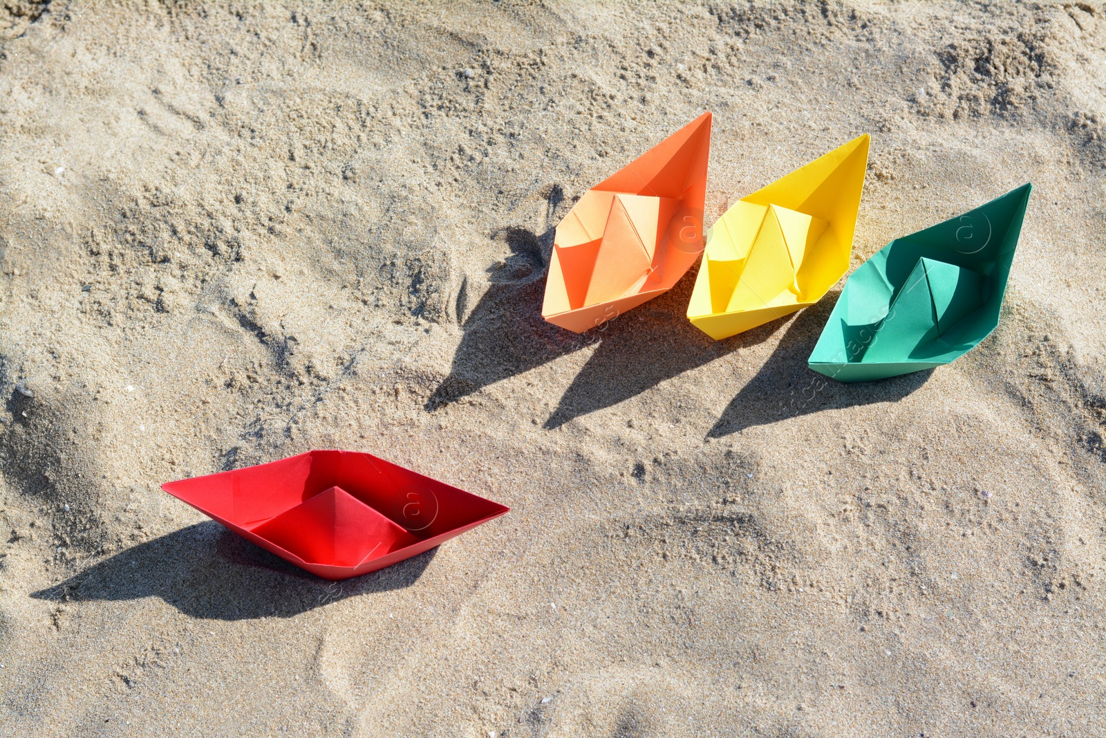 Photo of Many paper boats on sandy beach, above view