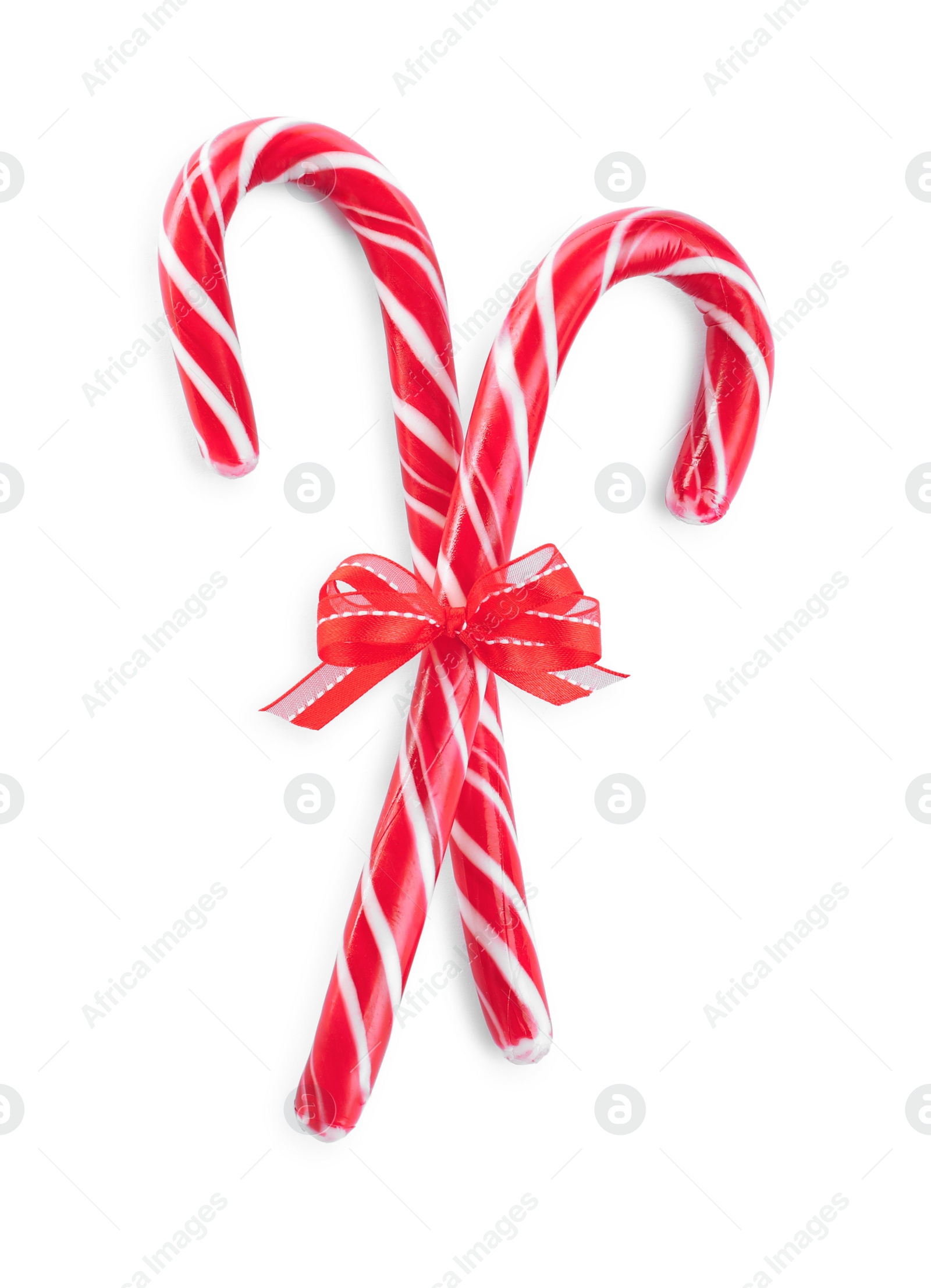 Photo of Sweet Christmas candy canes with red bow on white background, top view