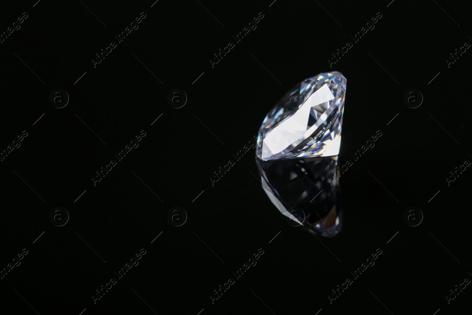 Photo of Beautiful shiny diamond on black mirror surface, space for text
