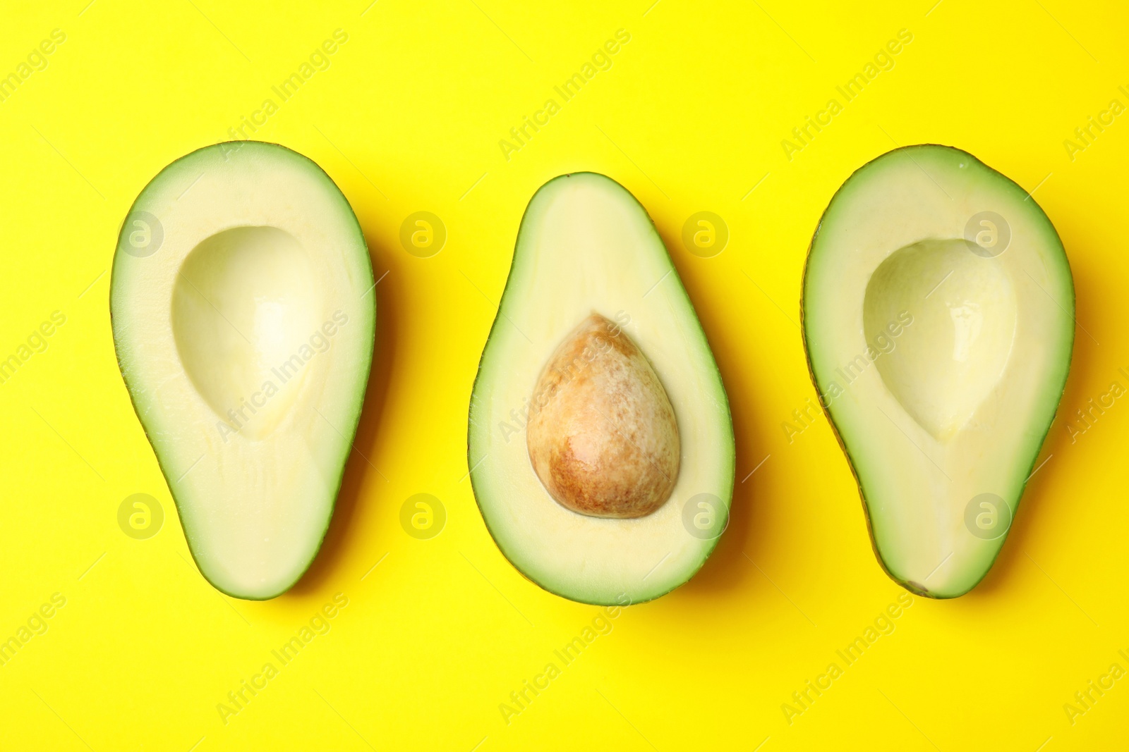 Photo of Cut fresh ripe avocados on yellow background, flat lay