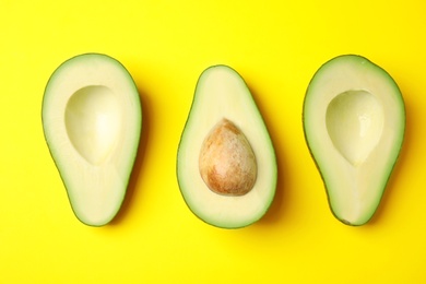 Cut fresh ripe avocados on yellow background, flat lay