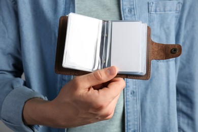 Photo of Man holding leather business card holder with blank cards, closeup