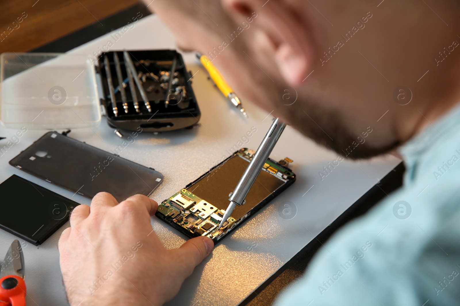 Photo of Technician repairing mobile phone at table, closeup