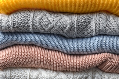 Photo of Stack of folded warm knitted sweaters, closeup