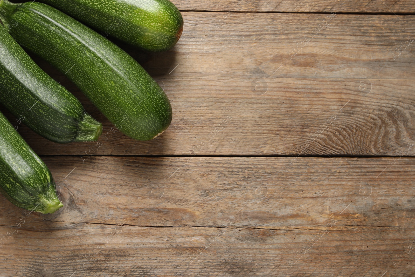 Photo of Raw ripe zucchinis on wooden table, flat lay. Space for text