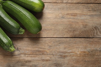 Photo of Raw ripe zucchinis on wooden table, flat lay. Space for text