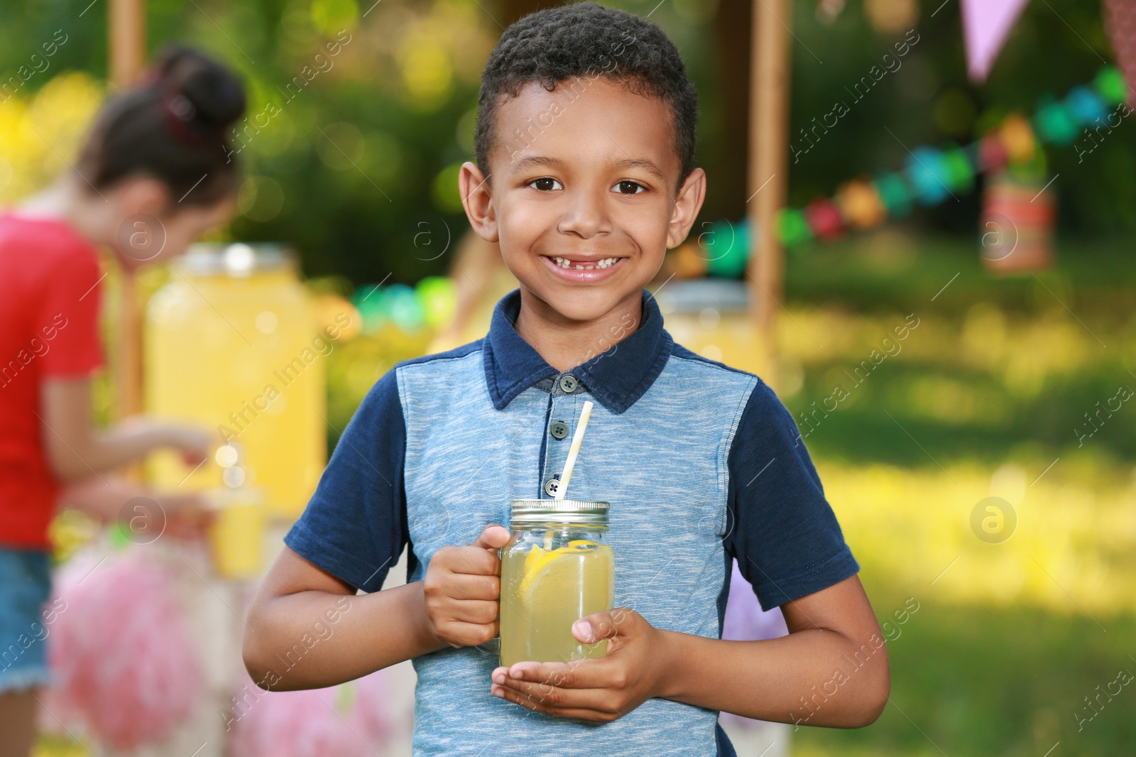 Photo of Cute little African-American boy with natural lemonade in park. Summer refreshing drink