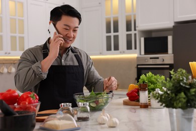 Man talking on smartphone while cooking in kitchen