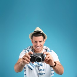 Photo of Male tourist taking picture against turquoise background, focus on camera