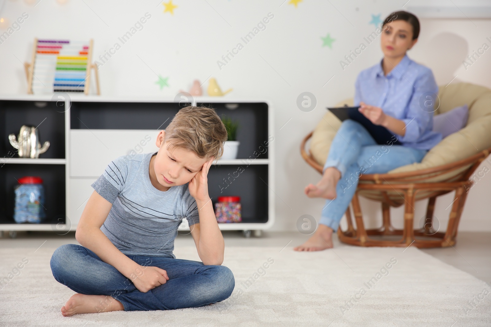 Photo of Sad little boy on carpet at child psychologist's office