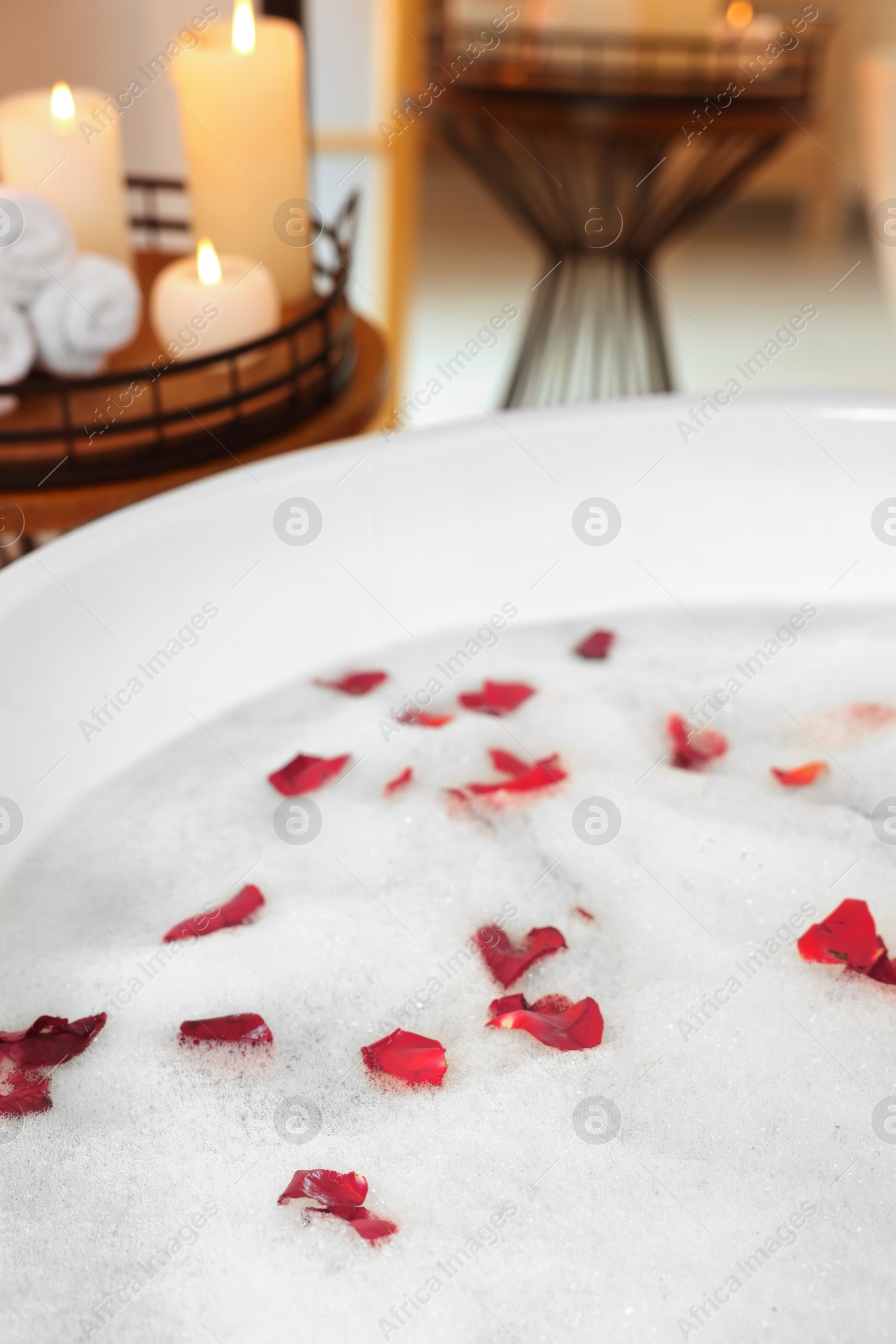 Photo of Foam and red rose petals in bath tub, closeup