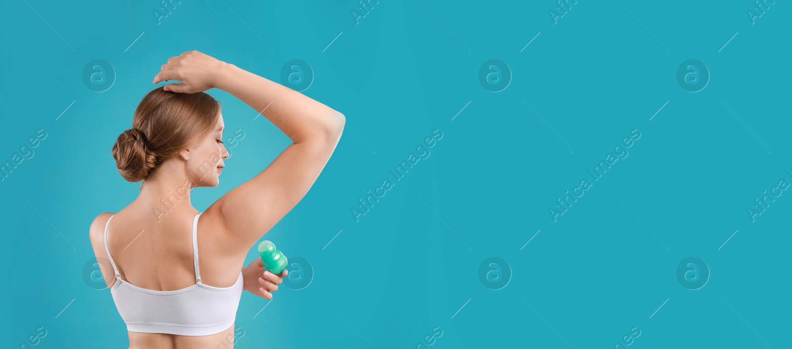 Image of Young woman applying deodorant to armpit on turquoise background, space for text. Banner design