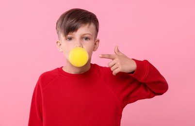 Photo of Boy blowing bubble gum on pink background