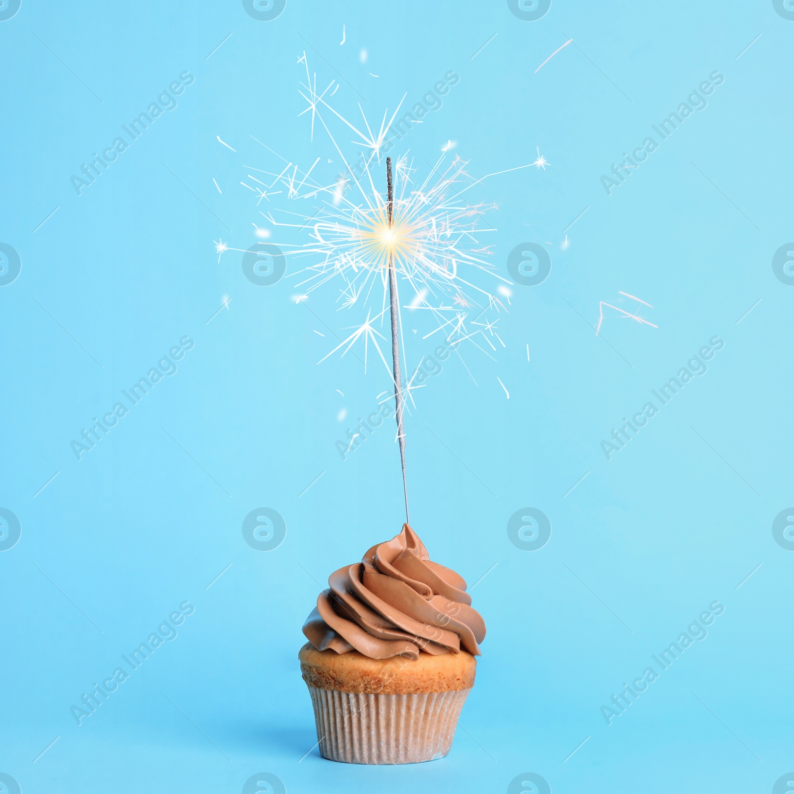 Image of Birthday cupcake with sparkler on light blue background