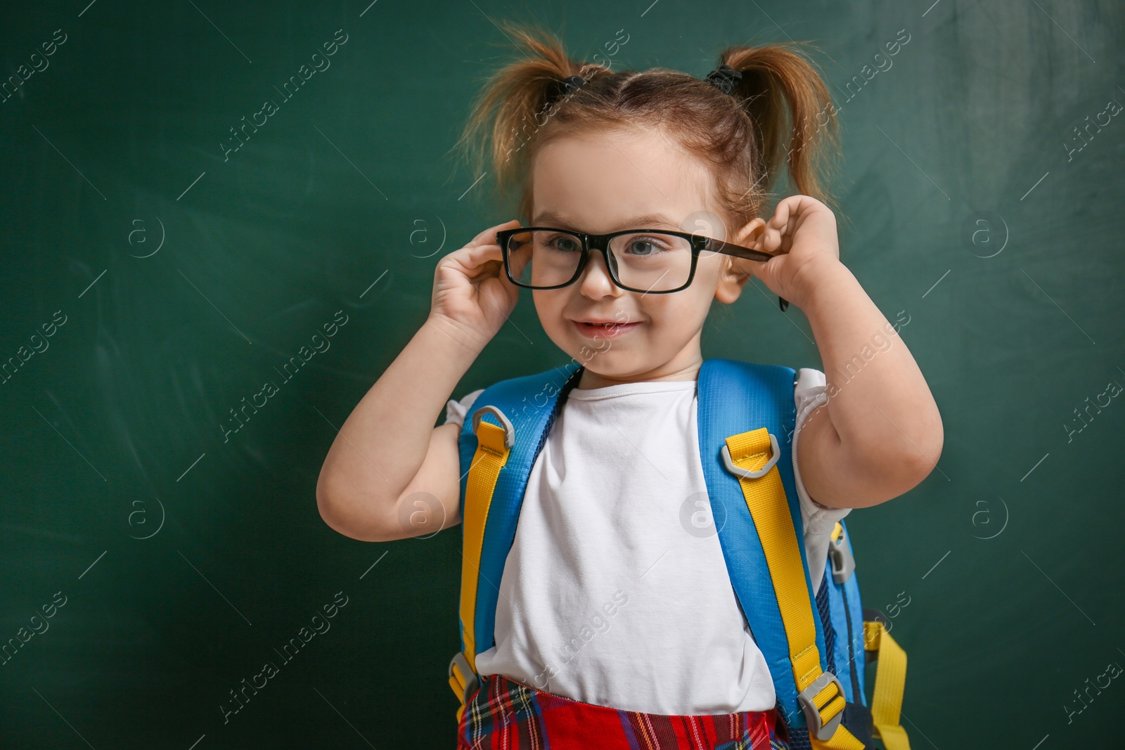 Photo of Cute little child wearing glasses near chalkboard. First time at school