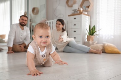 Happy parents watching their baby crawl on floor at home