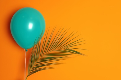 Green balloon and palm leaf on color background. Celebration time