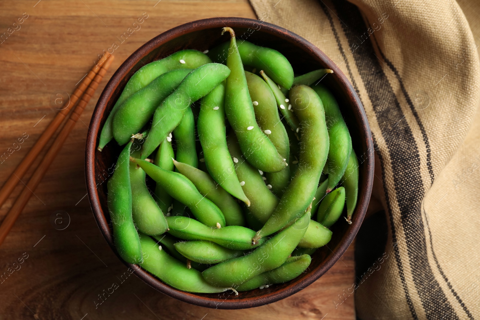 Photo of Green edamame beans in pods served on wooden table, flat lay