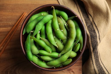 Photo of Green edamame beans in pods served on wooden table, flat lay