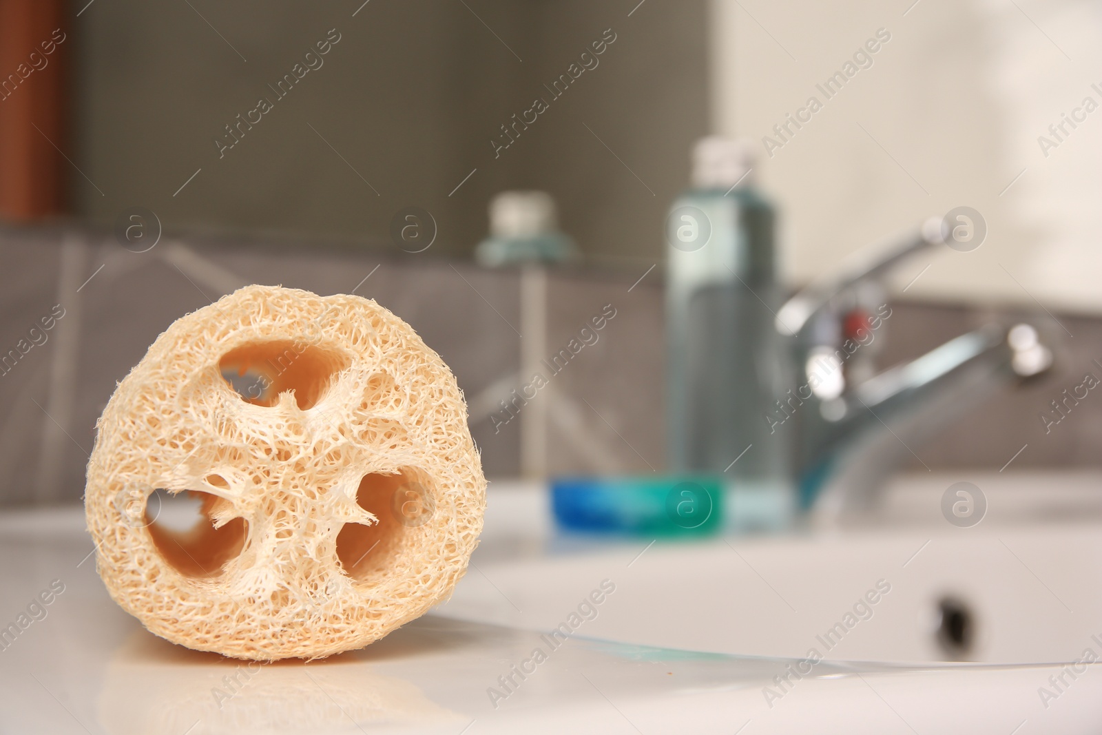 Photo of Loofah sponge on sink in bathroom, closeup. Space for text