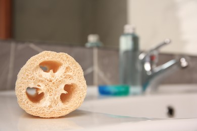 Loofah sponge on sink in bathroom, closeup. Space for text