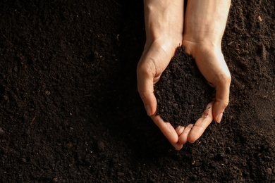 Photo of Woman with handful of soil outdoors, top view. Space for text