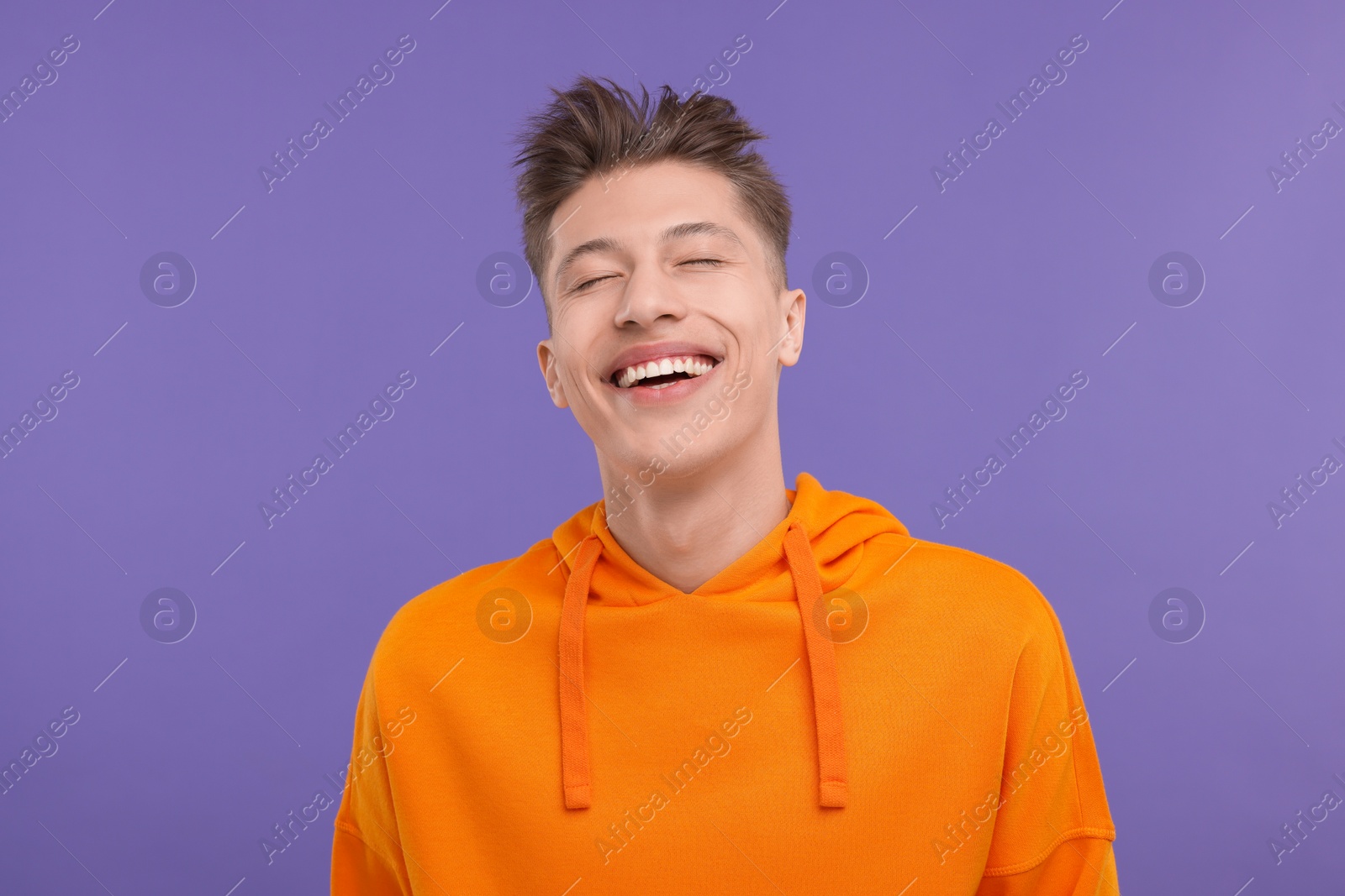 Photo of Portrait of young man laughing on violet background