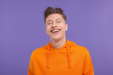 Portrait of young man laughing on violet background