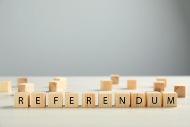 Photo of Word Referendum of wooden cubes on white table against light grey background. Space for text