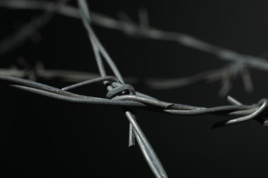 Photo of Metal barbed wire on dark grey background, closeup