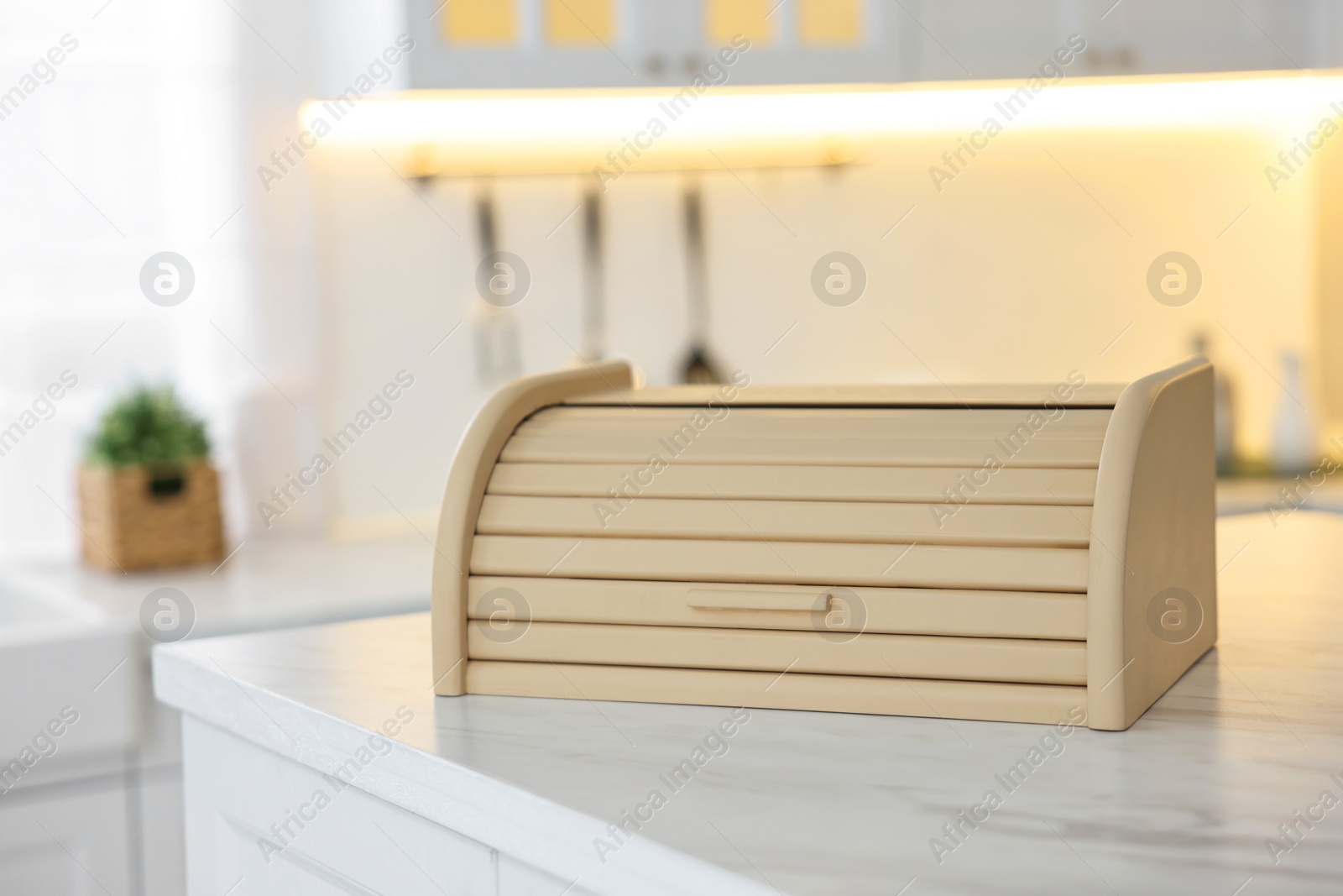 Photo of Wooden bread box on white marble table in kitchen