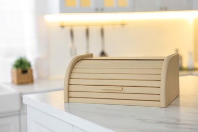 Photo of Wooden bread box on white marble table in kitchen