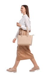 Young woman with stylish bag walking on white background