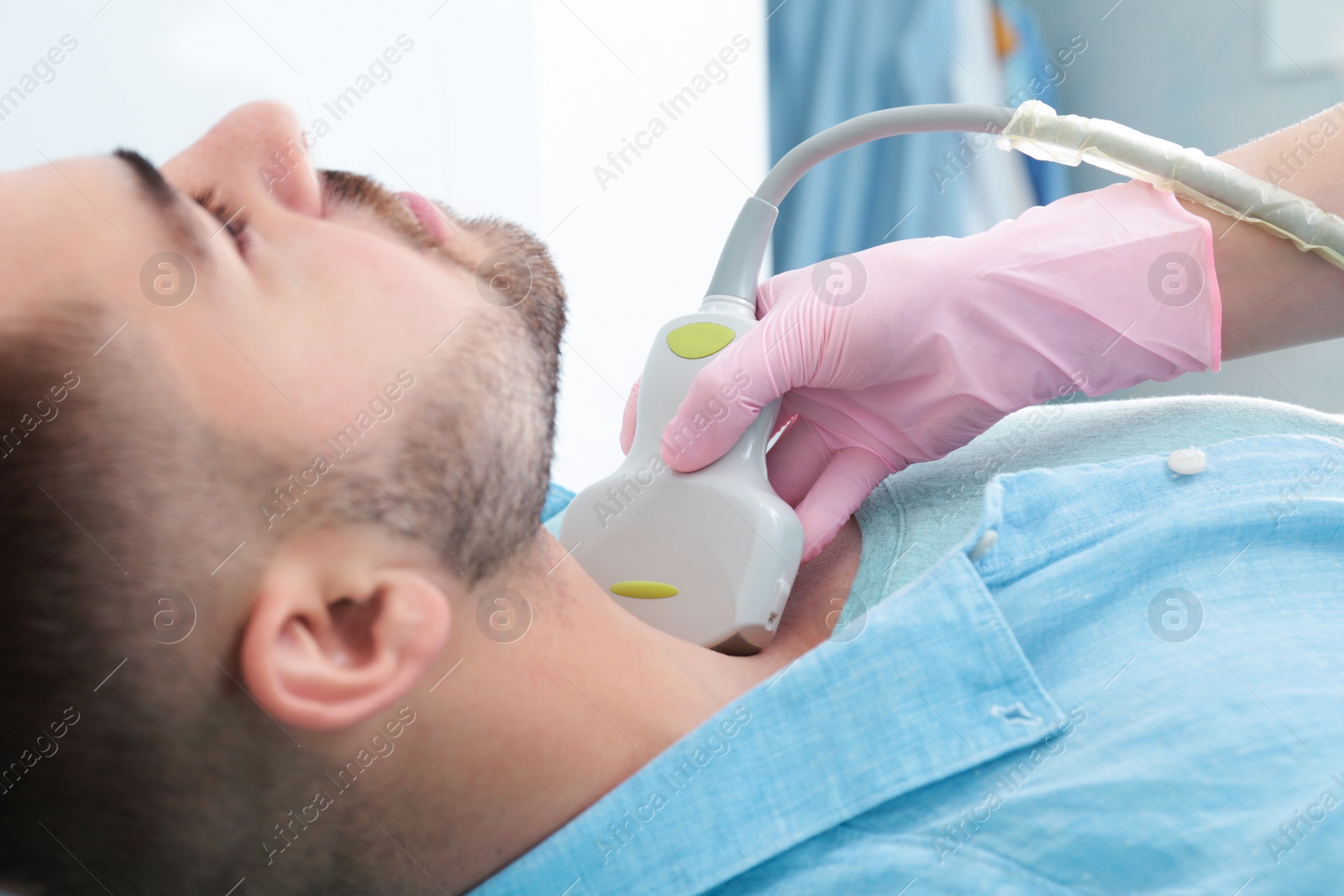 Photo of Doctor conducting ultrasound examination of patient's neck in clinic, closeup