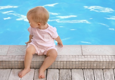 Photo of Little baby sitting near outdoor swimming pool. Dangerous situation