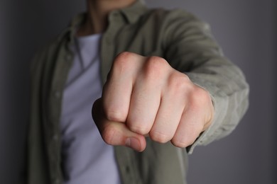 Photo of Man showing fist with space for tattoo on grey background, selective focus