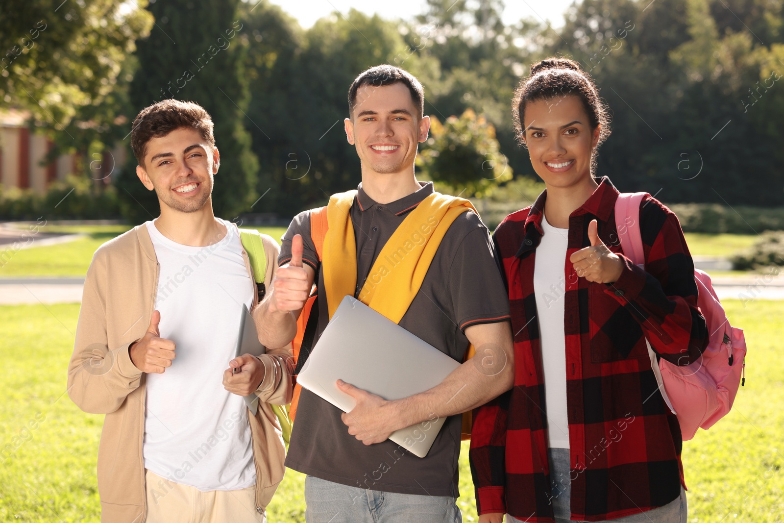 Photo of Happy young students showing thumbs up in park