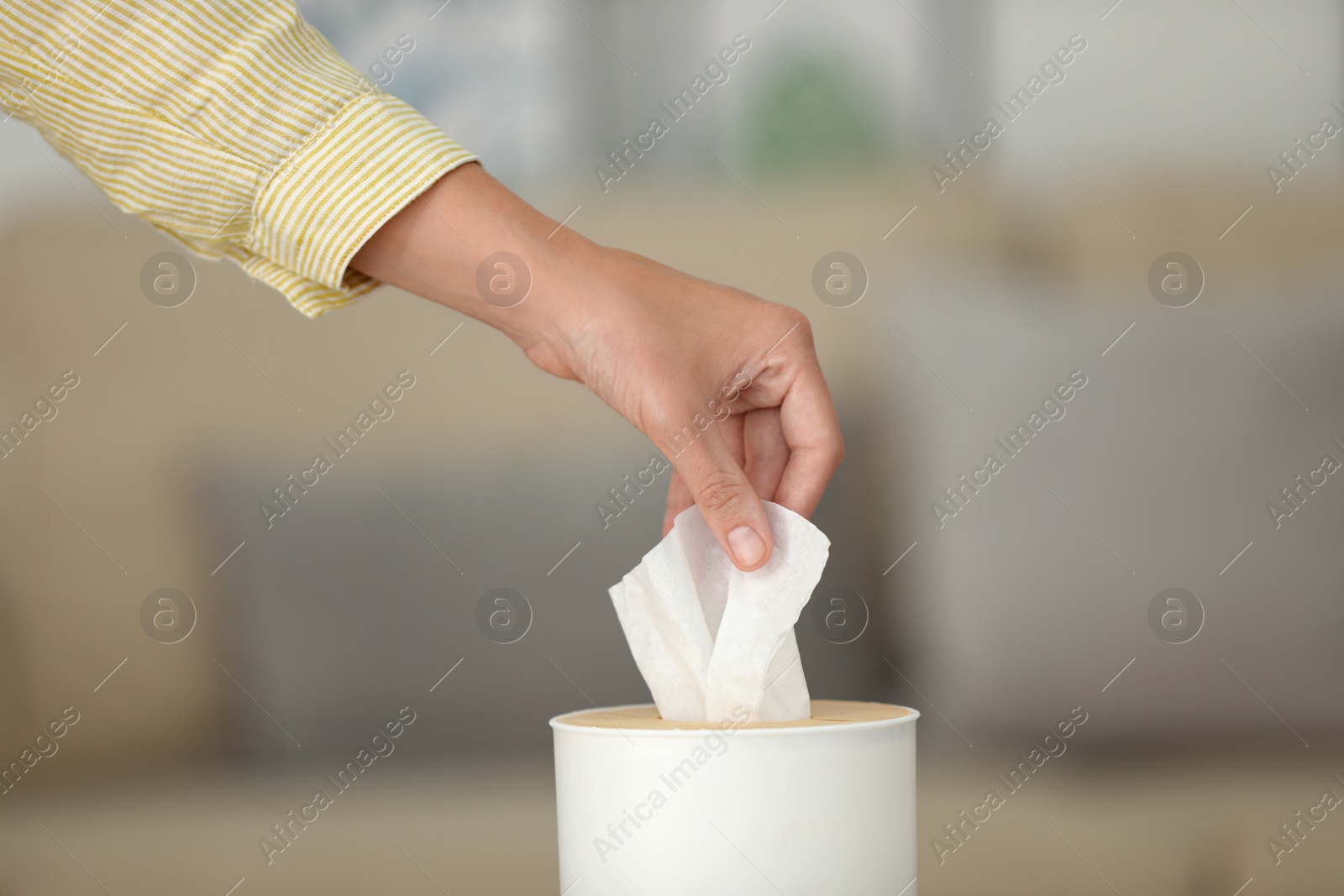 Photo of Woman taking paper tissue from holder indoors, closeup