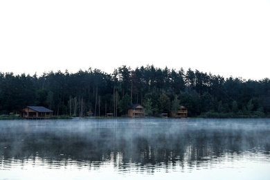 Beautiful landscape with forest and houses near lake. Camping season