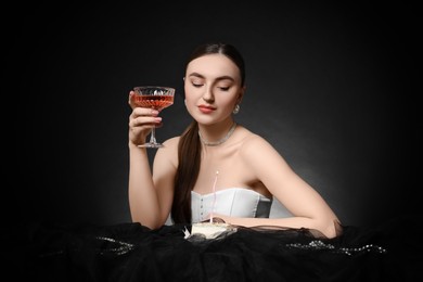 Photo of Fashionable photo of attractive woman with glass of wine and her Birthday cake on black background