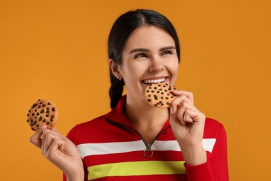 Photo of Young woman with chocolate chip cookies on orange background