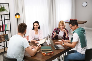 Young people discussing group project at table in library